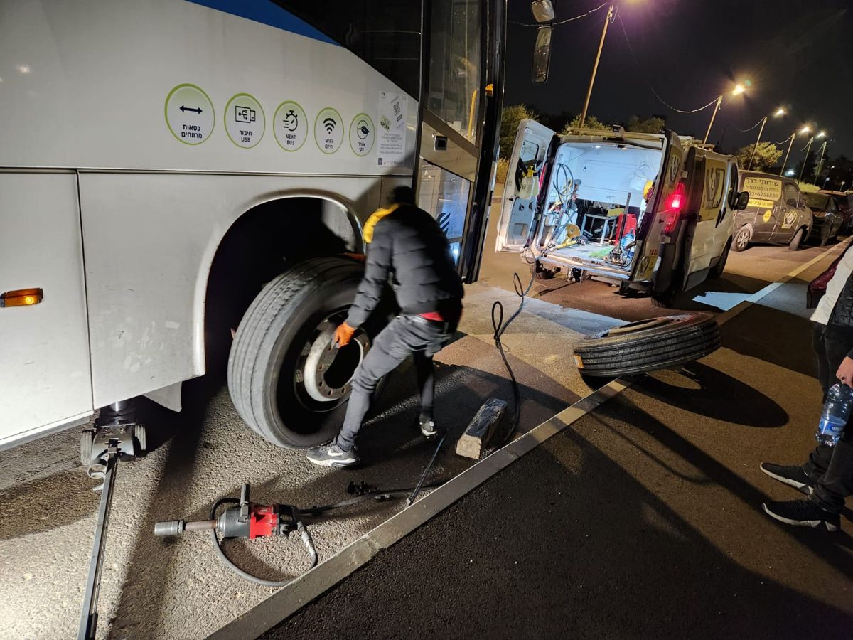 טכנאי של פנדה מחליף גלגל לאוטובוס בלילה
