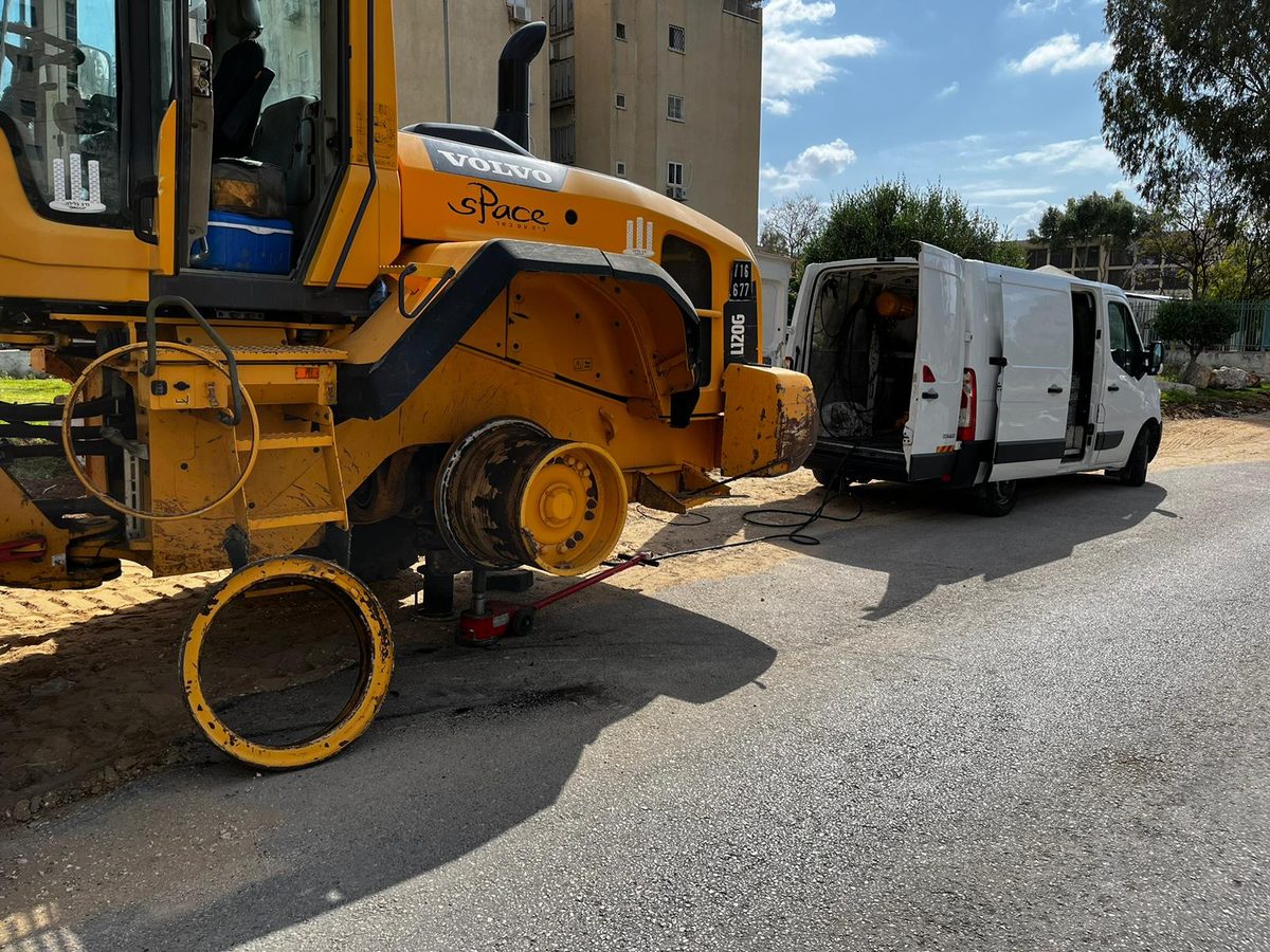 כלי צמ״ה מורם עם גלגל שהוסר, וניידת שירות מאחור