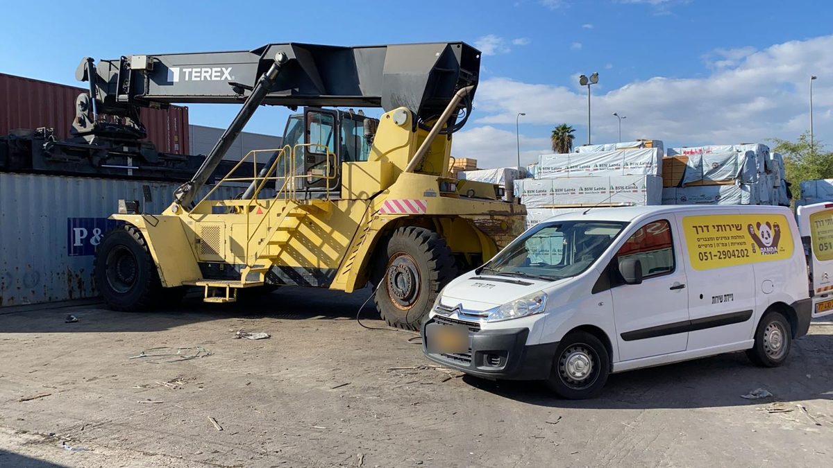 ניידת פנדה ליד מנוף מכולות גדול באתר תעשייה