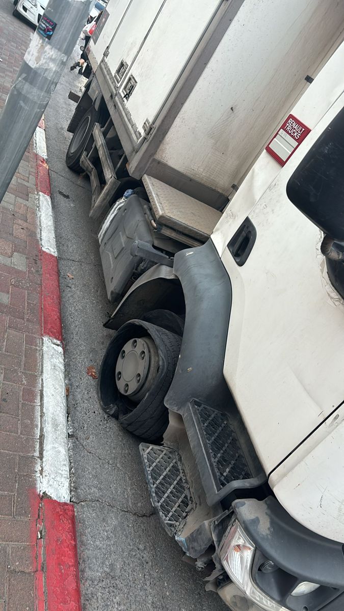 משאית עם צמיג קדמי פגוע שעומדת צמוד למדרכה